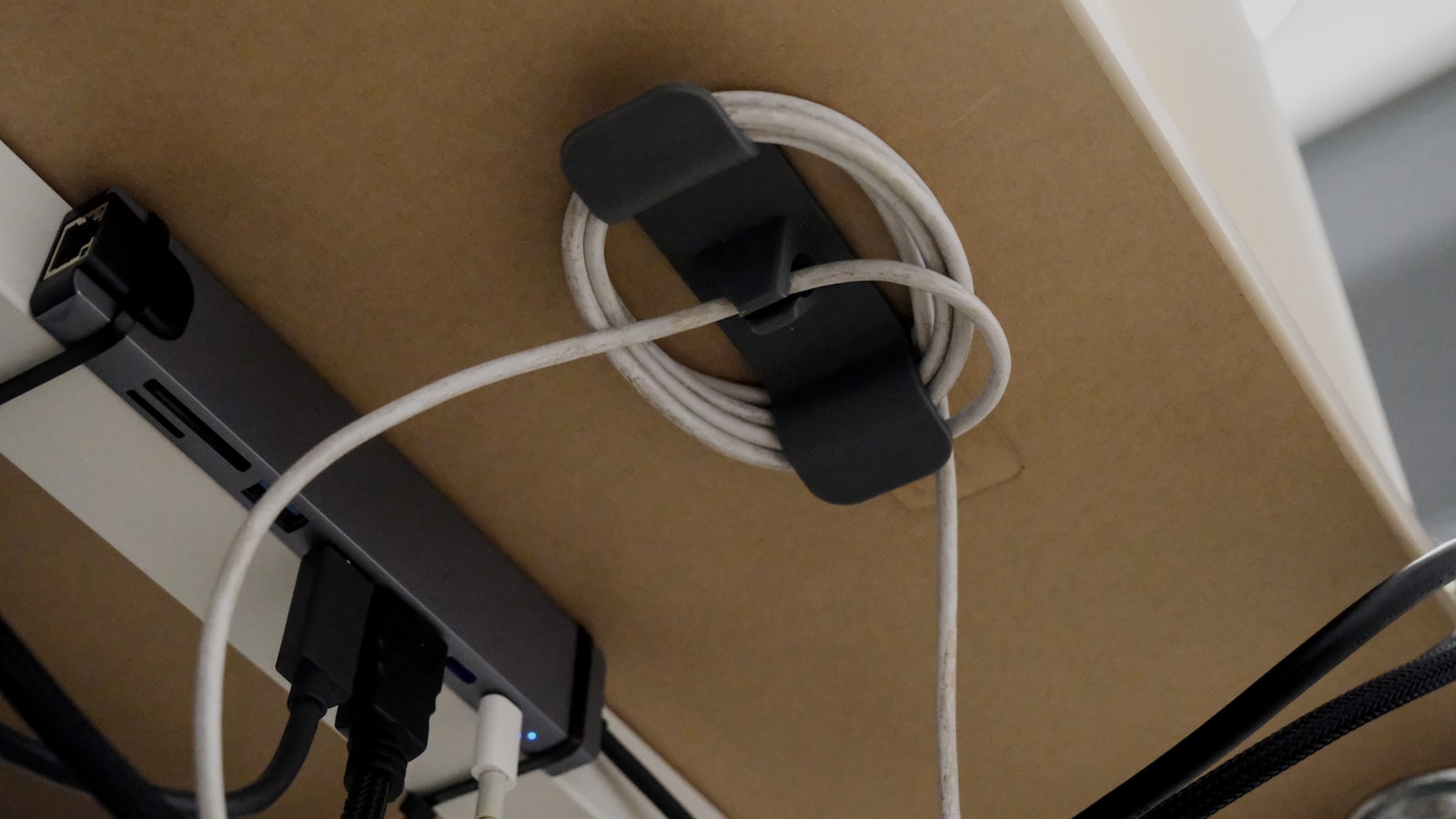 A cable clip organizing coiled cords under a desk
