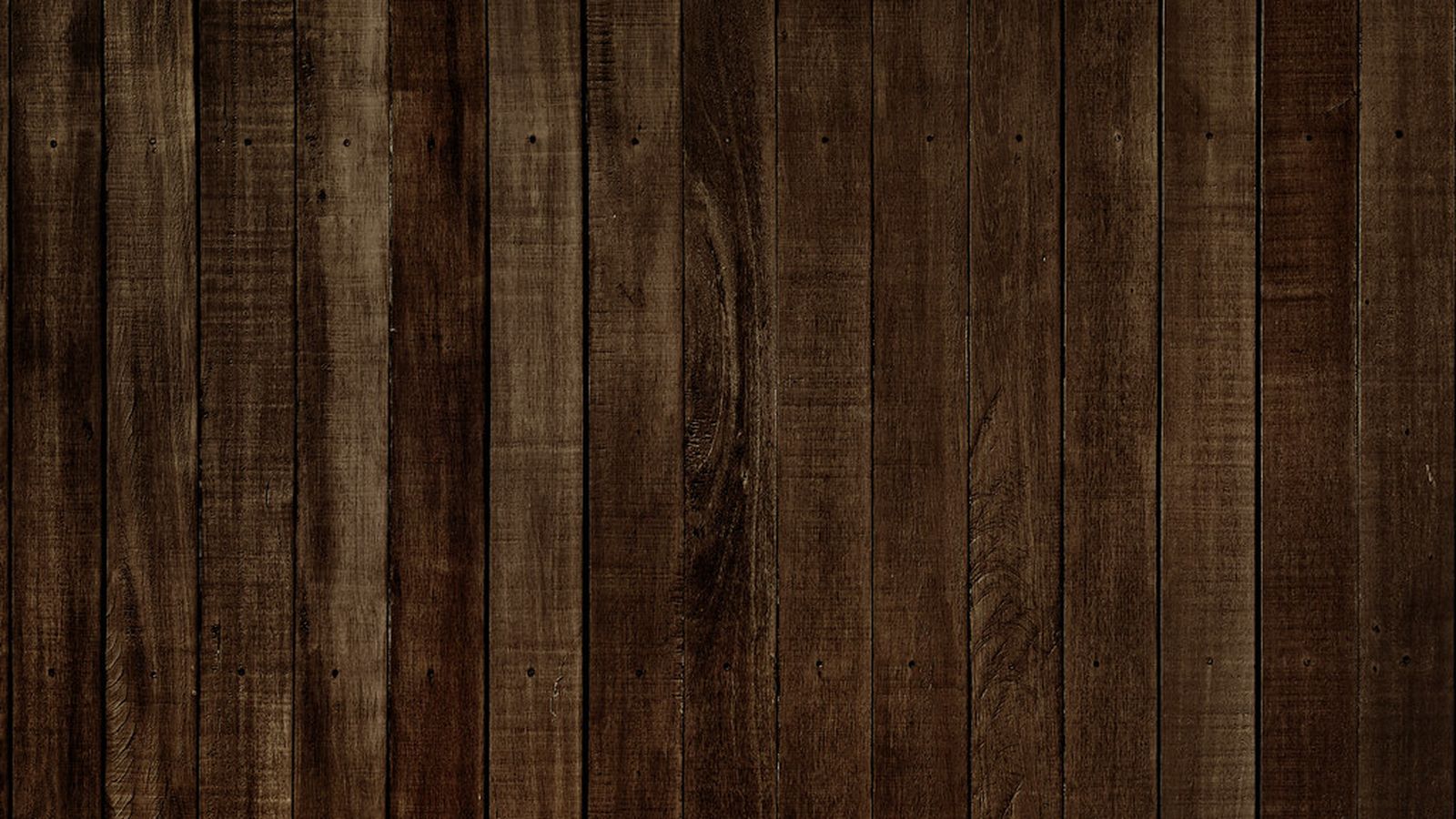 Close-up of dark reclaimed wood plank flooring with visible grain and nail holes