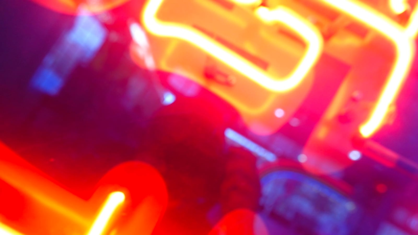 Out-of-focus neon tubing glowing magenta, red and blue against a dark background