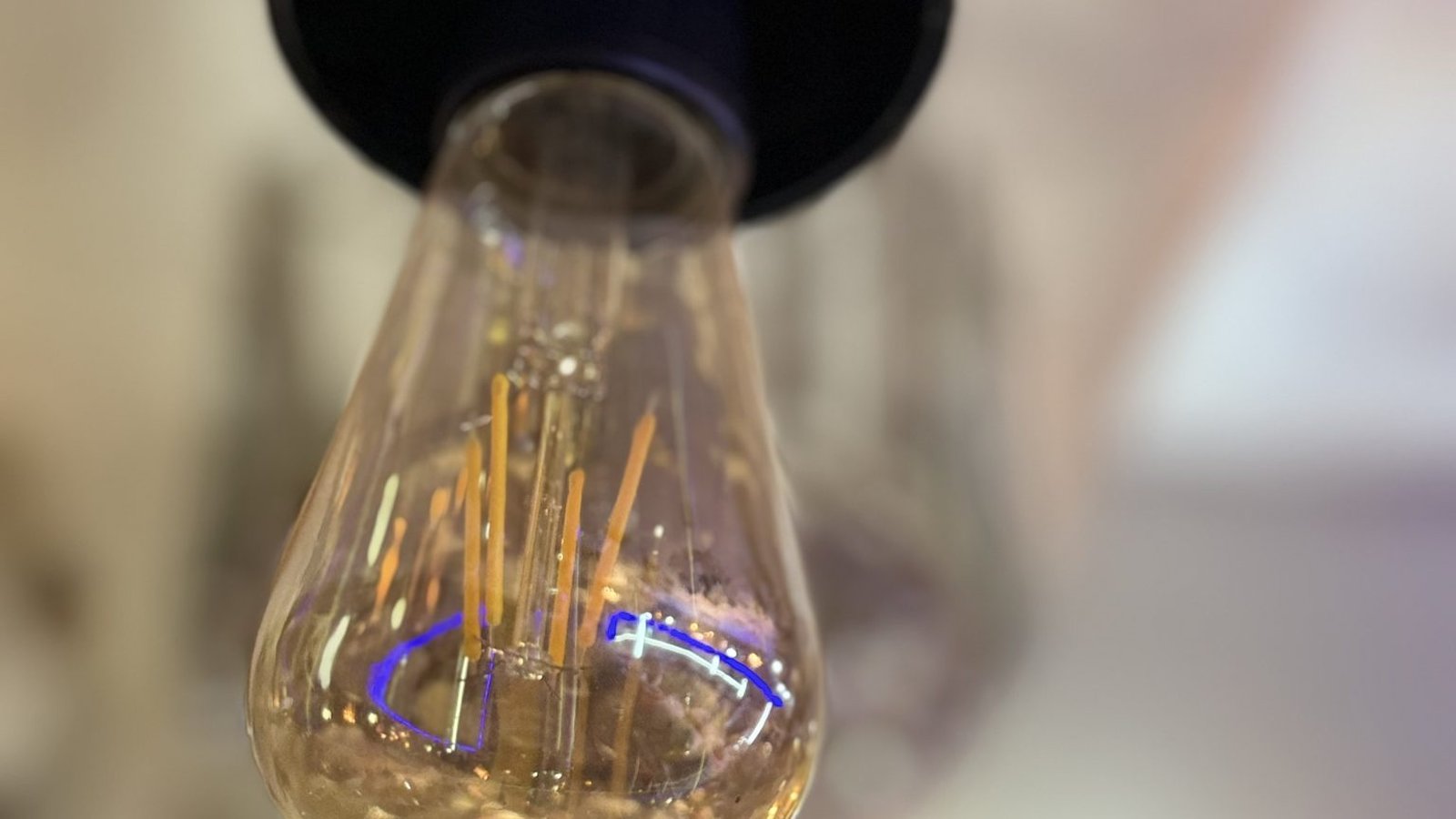 Extreme close-up of an unlit vintage filament light bulb hanging from a black fixture