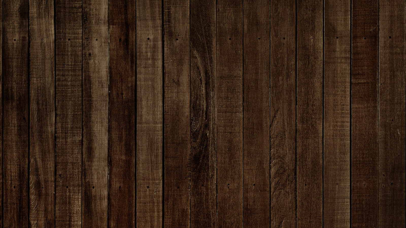 Close-up of dark wood plank flooring with visible grain, knots and nail marks