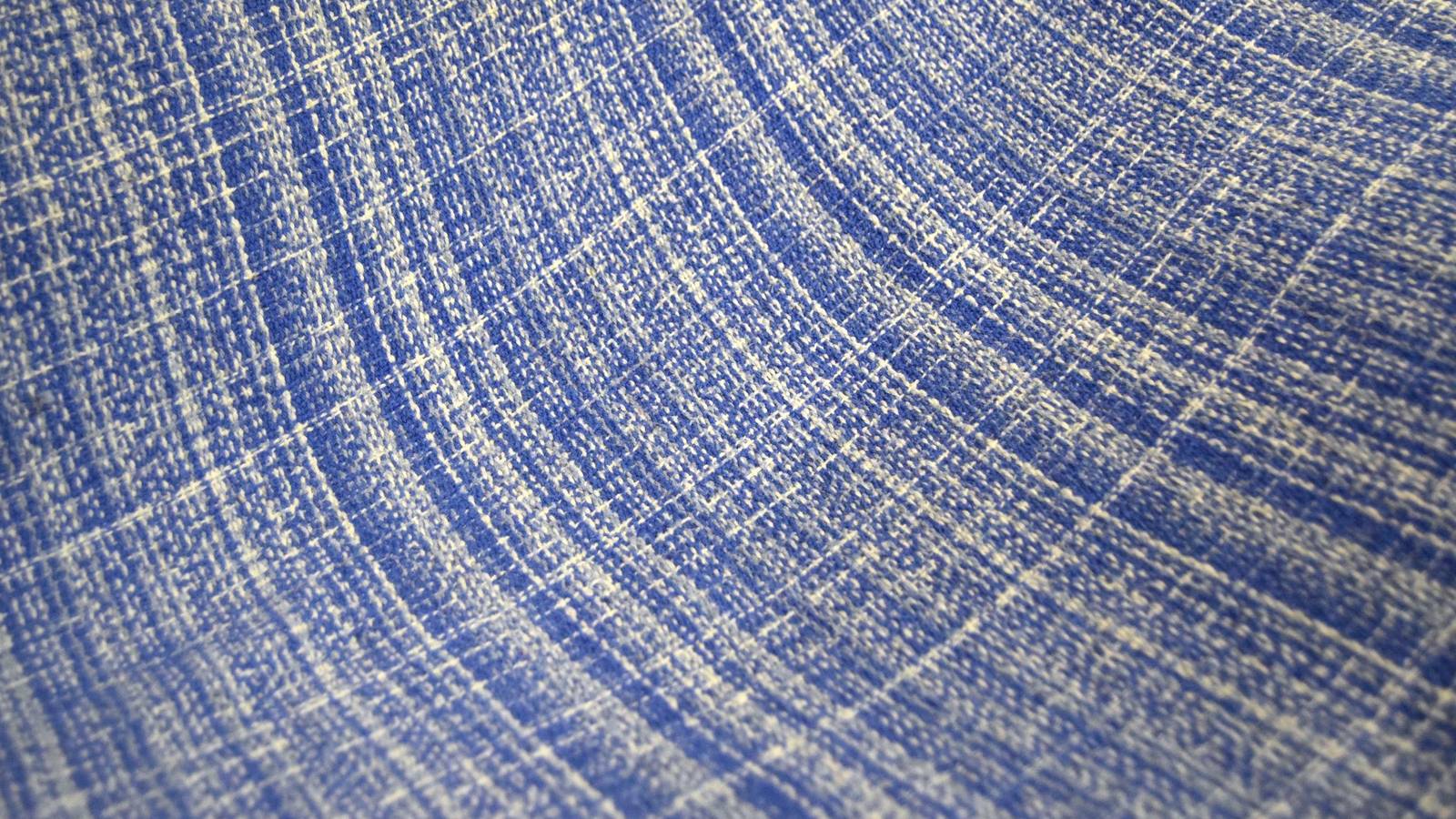 Extreme close-up of woven blue fabric texture, showing the individual crossed threads