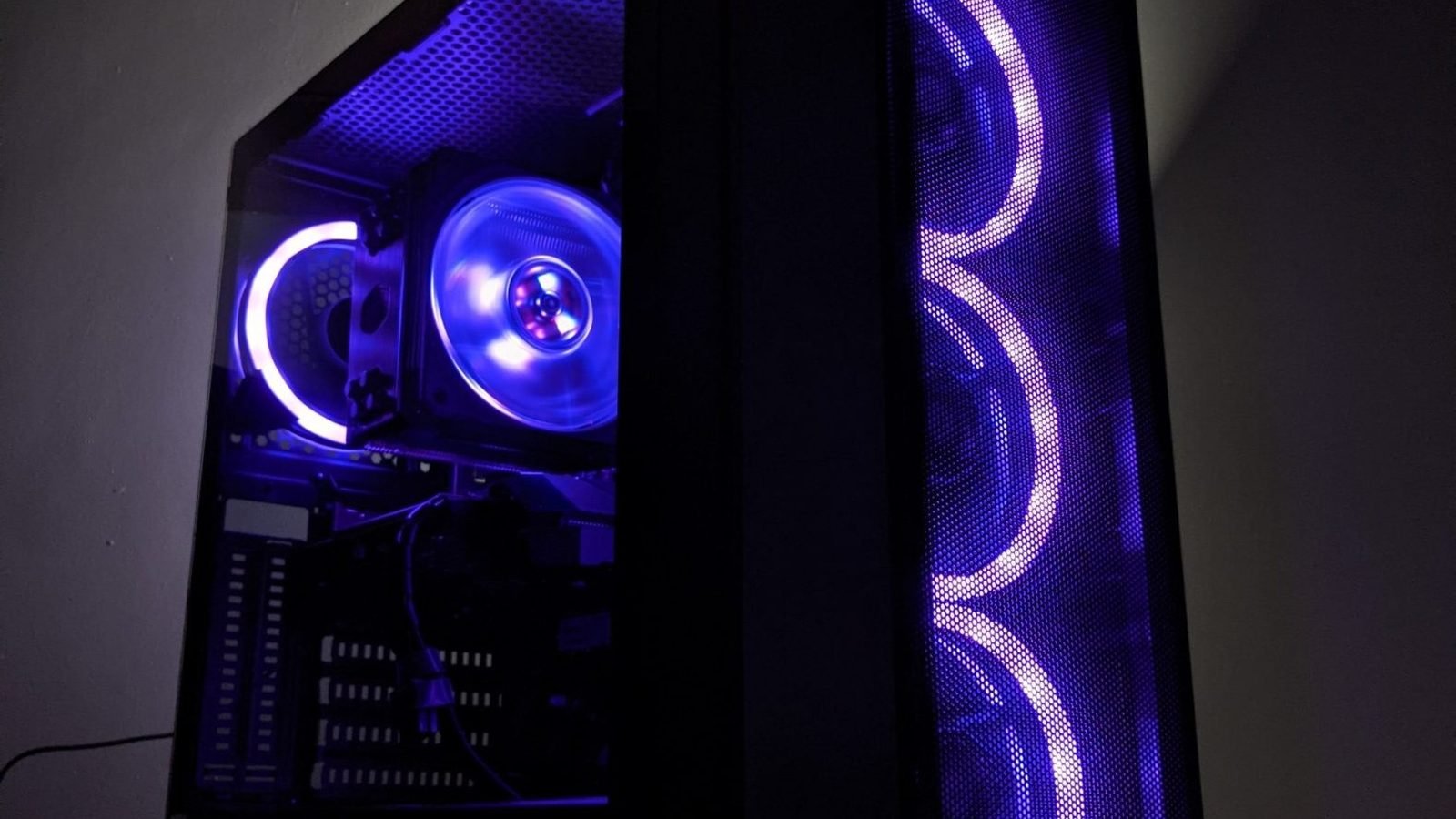 Close-up inside a PC case with deep blue and violet RGB lighting on the CPU cooler and front intake fans