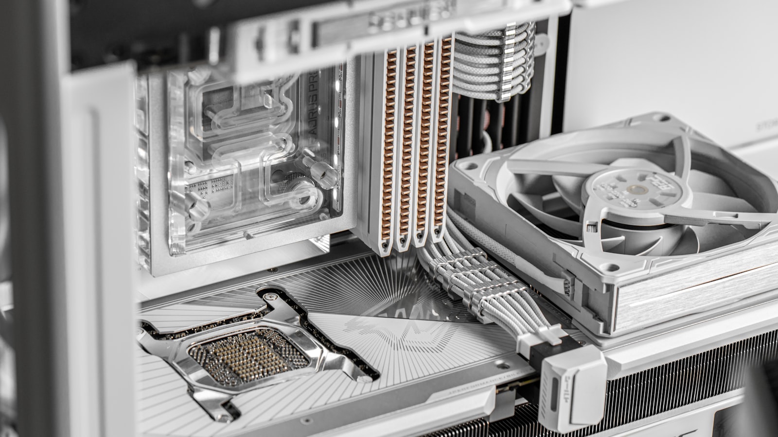 Close-up inside a white PC case showing a CPU socket, water block, heatsink fins, and a white cooling fan