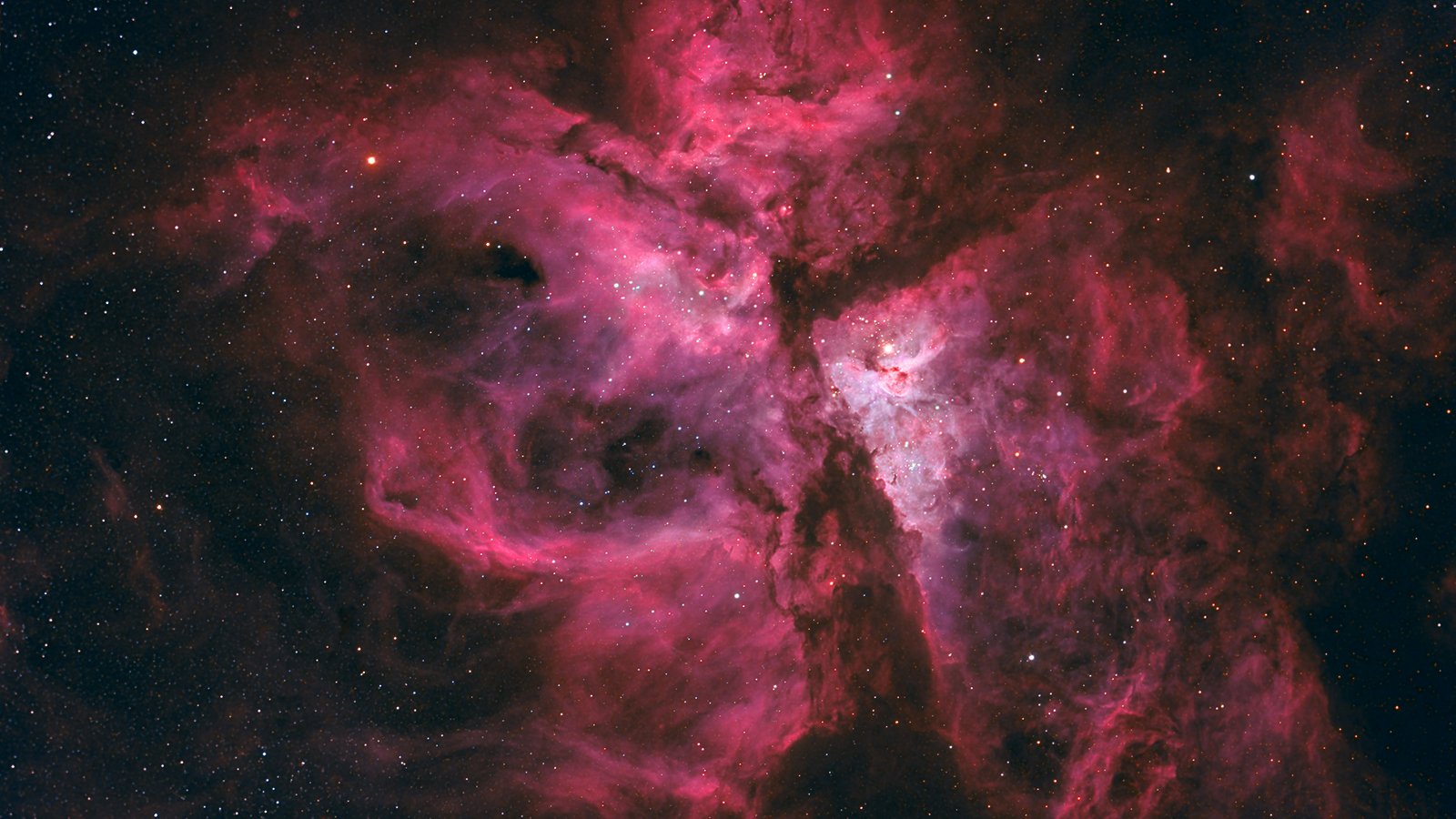 Dense magenta and violet star-forming nebula clouds with dark dust lanes, from a wide-field astrophotograph