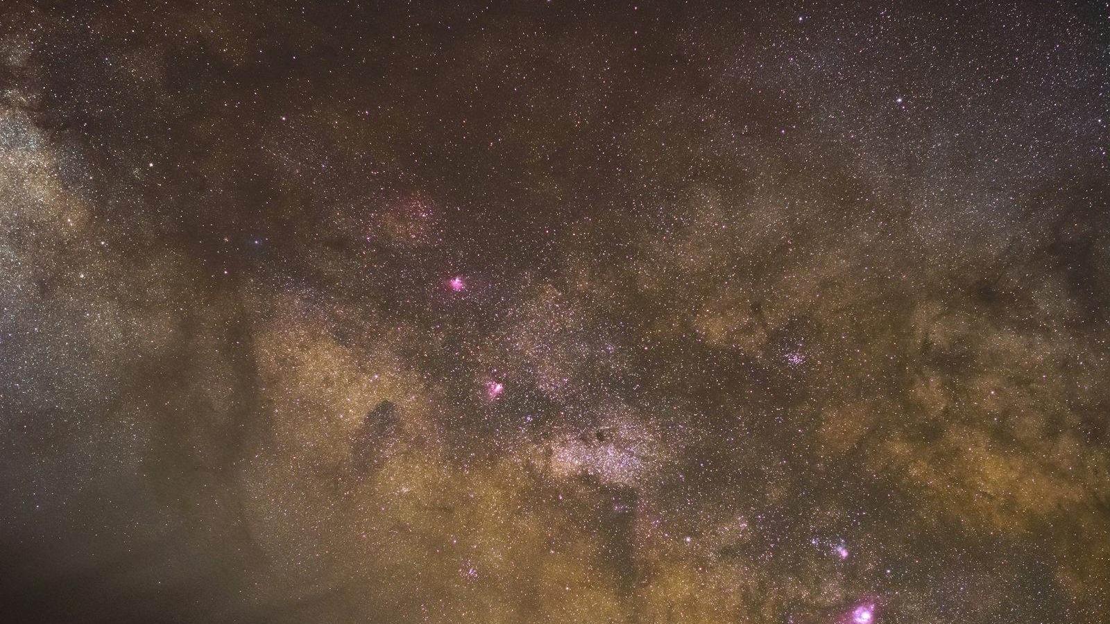Dense star field and purple-toned nebula clouds across the Milky Way