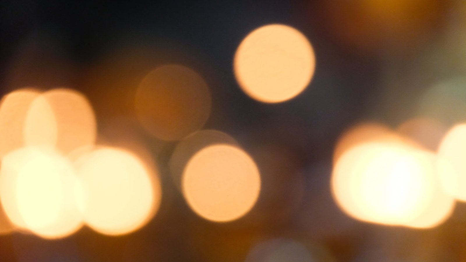 Blurred warm bokeh circles of golden light against a dark background