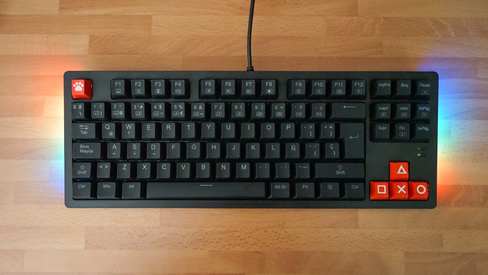 A backlit mechanical keyboard with custom keycaps sitting on a wooden desk